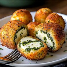 a white plate topped with mini rolls covered in cheese and spinach sauce next to a fork