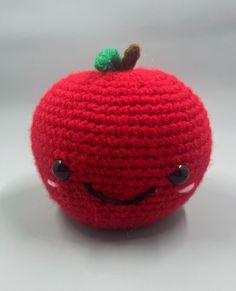 a red crocheted apple with eyes and a green leaf on it's top