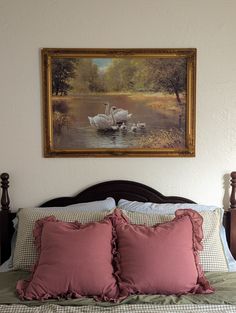 a painting hanging above a bed with two swans on it