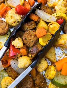 two tongs are sitting on top of a dish full of vegetables and meatballs