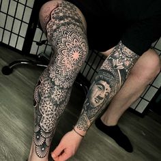 a man is sitting on the floor with his legs covered in tattoos