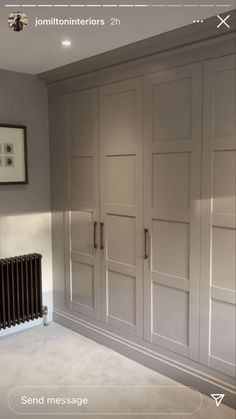 an empty room with white walls and gray cupboards on the wall, next to a radiator