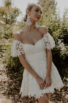 a woman in a white dress posing for the camera with her hands on her hips