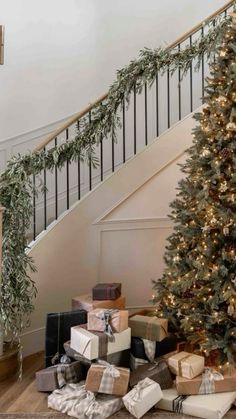 a christmas tree with presents under the stairs