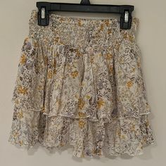 Cream Floral Skirt With Yellow Purple And Brown Flower Design And Textured Fabric Super Cute Layered Floral Skirt Perfect For Summer And As A Beach Or Pool Coverup Perfect Condition Never Worn Completely New Elastic Waist Super Comfy And Flattering Size M Length About 13.5 Inches Waist About 11.5 No Damage, Rips Or Stains From A Smoke Free And Pet Free Clean Household Reasonable Offers Are Welcome :) Feel Free To Ask Me Questions Below Yellow Tiered Skirt With Floral Print, Flowy Floral Print Mini Skirt, Flowy Yellow Ruffled Skirt, Yellow Bohemian Bottoms With Ruffled Skirt, Yellow Bohemian Ruffled Skirt Bottoms, Yellow Tiered Mini Skirt For Summer, Yellow Ruffled Mini Skirt, Yellow Tiered Skirt With Elastic Waistband, Yellow Flowy Tiered Mini Skirt