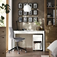 a white desk and chair in a room with pictures on the wall