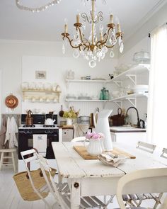 a dining room table with chairs and a chandelier hanging from it's ceiling