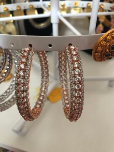 several bracelets are hanging from a rack in a jewelry store with gold and silver accessories