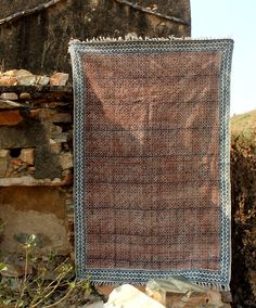 a brown and blue rug sitting on top of a stone wall next to a building