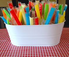 a bucket filled with lots of different colored toothbrushes on top of a red and white checkered table cloth