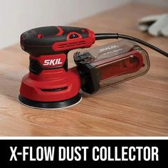 a red and black sanding machine sitting on top of a wooden table with the words skil x - flow dust collector