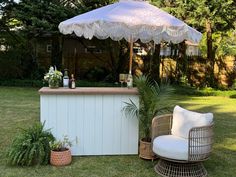 an outdoor bar is set up in the yard with chairs and umbrellas over it