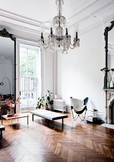 a living room filled with furniture and a chandelier hanging from the ceiling next to a window