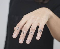 a woman's hand with two zodiac signs tattooed on her left thumb and fingers