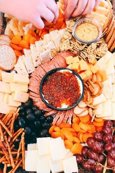 a platter filled with cheeses, crackers, and other snacks is being served