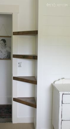 an empty room with some shelves and a baby's photo hanging on the wall