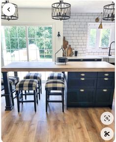 a kitchen island with stools in front of it and an open window behind it