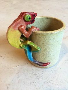 a ceramic cup with a lizard figurine on it