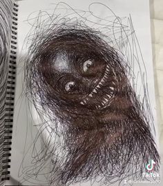 a drawing of a gorilla face on top of a piece of paper next to a spiral notebook