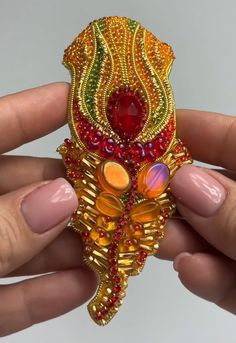 a person holding a colorful brooch in their hand