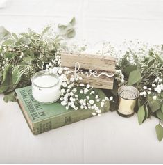 a table topped with books and flowers next to a candle