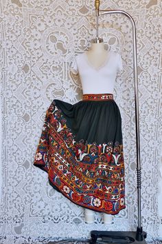 I've always really loved Indian mirror embroidery. This skirt features the classic dense embroidery, with little mirrors intricately sewn in. The piece is made from a heavy woven cotton, with a full silhouette and hook closure. It is in very good shape! It has no size tag, but would best fit a size medium, see measurements for details.  All measurements taken flat across. Measurements Waist: 16" Hip: 35" Length: 36" Fitted Folk Style Skirt, Folk Style Multicolor Embroidered Skirt, Folk Style Embroidered Multicolor Skirt, Bohemian Multicolor Embroidered Skirt, Long Embroidered Cotton Skirt, Bohemian Fitted Skirt With Multicolor Embroidery, Fitted Cotton Skirt For Festivals, Bohemian Embroidered Festival Skirt, Bohemian Embroidered Skirt For Festivals