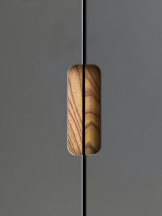 a close up of a wooden object on a metal pole in front of a gray wall