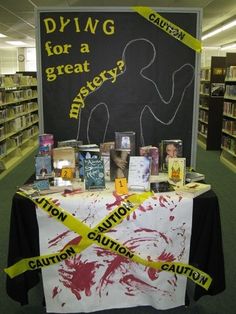 a table covered in books with caution tape around it and a chalkboard behind it