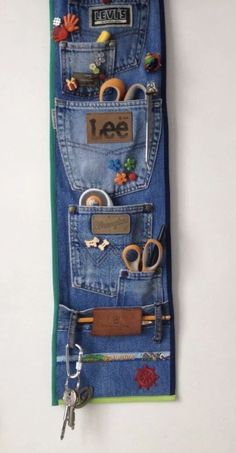 an old pair of jeans hanging on a wall with some scissors and other items in it