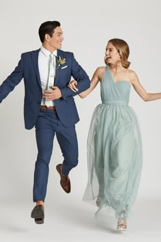 a man and woman dressed in formal wear are running through the air with their arms around each other