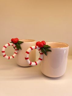 two coffee mugs decorated with candy canes and holly