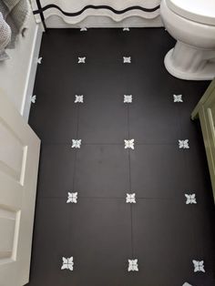 a bathroom with black and white tile flooring in it's center, next to a toilet