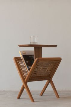 a wooden table with a magazine holder on it and a glass sitting on top of it