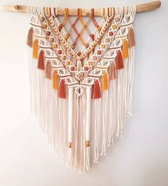 a macrame wall hanging with tassels and beads on a wooden stick