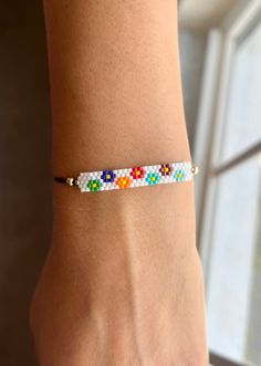 a woman's hand wearing a bracelet with multicolored bead designs on it