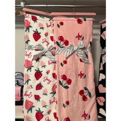 two baby swaddles hanging on a clothes rack with apples and cherries on them