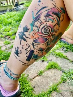 a woman's leg with tattoos on it and her foot in the grass next to a bench