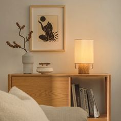 a living room with a lamp and some books on the shelf next to a couch