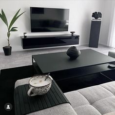 a black and white living room with modern furniture in the center, large flat screen tv on the wall