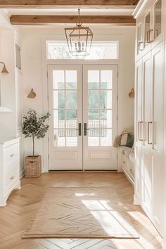 an entryway with white doors and wooden floors is seen in this image from the front door