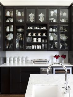 a kitchen filled with black cabinets and white counter tops next to a sink under a faucet