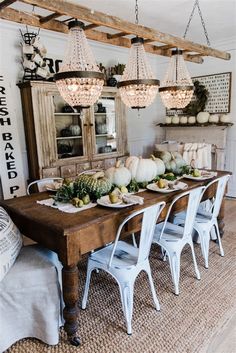 the dining room table is set with white pumpkins and greenery