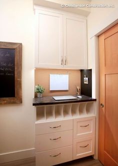 a kitchen with white cupboards and black counter top next to a chalkboard on the wall