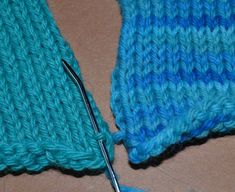 a pair of scissors cutting through the yarn on top of a piece of blue knitted material