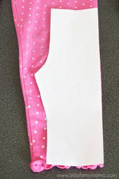 pink and white polka dot leggings with blank paper in the back pocket, sitting on carpet