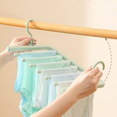 a woman is trying to hang her clothes on a rack with a wooden pole and hooks