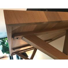 a close up of a wooden table with a plant in the background