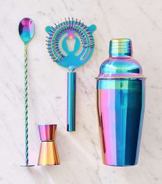 a colorful cocktail shaker, spoon and cup on a marble surface