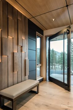 a bench sitting in front of a wooden wall with glass doors leading to the outside