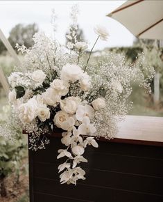 a bouquet of white flowers sitting on top of a wooden table next to an umbrella